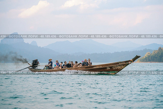 Thailand, Khao Sok 2025 14 02: Cruise the calm waters of Thailand on a long-tail boat, exploring the beauty of lakes and mountains during a scenic tour. The female helmsman Loki talks about gender equality in Thailand. Стоковое фото, фотограф Владимир Разгуляев / Фотобанк Лори