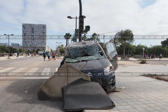 The aftermath of hurricane Dana in Valencia, Spain - Devastating consequences of flooding in Valencia, damaged car and debris on city street. Стоковое фото, фотограф Данил Руденко / Фотобанк Лори