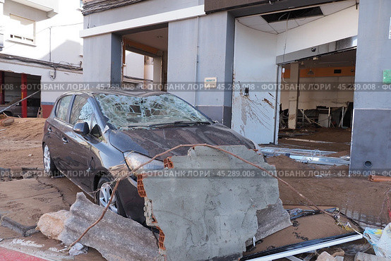 The aftermath of hurricane Dana in Valencia, Spain - Devastating flood aftermath in Valencia, damaged car and building. Стоковое фото, фотограф Данил Руденко / Фотобанк Лори
