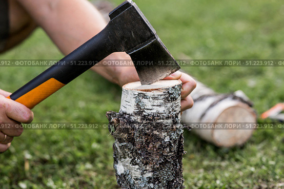 The axe is in the man's hand and is stuck in a birch log. Preparing firewood for the winter season. Logging. Timber, tools for cutting wood. Стоковое фото, фотограф Photojuli / Фотобанк Лори