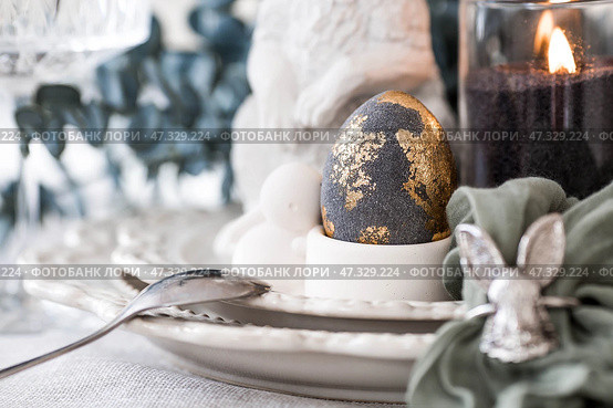 The banner. Table setting. A plate with a rabbit and a napkin, Easter eggs with gilding and a branch of eucalyptus on a linen tablecloth. The concept of a bright Easter holiday. Стоковое фото, фотограф Photojuli / Фотобанк Лори