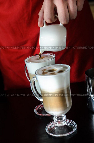 the bartender Barista behind the counter making coffee latte, pouring and prevents. Стоковое фото, агентство Ingram Publishing / Фотобанк Лори