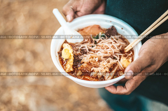 The beggar stands to hold with noodles in a foam cup complete with chopsticks and spoons. Стоковое фото, агентство Ingram Publishing / Фотобанк Лори