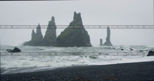 The black sand beach of Reynisfjara with waves hitting the shore on foggy rainy stormy day Vik, Icel. Стоковое видео, видеограф Igor Tichonow / Фотобанк Лори