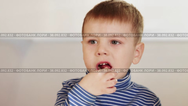 The boy eats candy and tries to get stuck pieces. Стоковое видео, видеограф Потийко Сергей / Фотобанк Лори