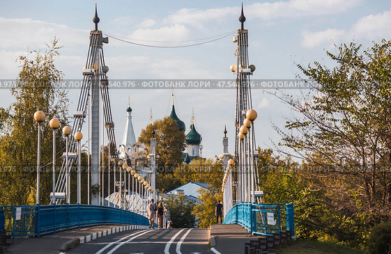The bridge over the Kotorosl River to Damansky Island and people passing by. Yaroslavl, Russia. Редакционное фото, фотограф Photojuli / Фотобанк Лори