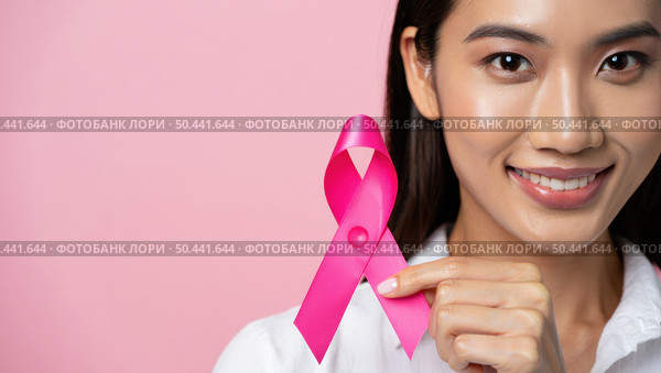 The close up photo shows an Asian woman with black hair and a bright smile holding a pink ribbon. The delicate pink background symbolizes support in the fight against breast cancer. Стоковое AI-изображение, AI-художник Светлана  Громак / Фотобанк Лори