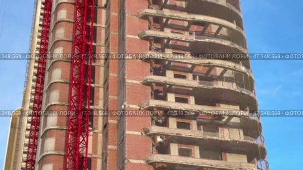 The construction of a multistory building with a prominent red crane is noteworthy. Стоковое видео, видеограф Vladimir Vintonjak / Фотобанк Лори