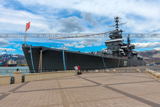 The cruiser "Mikhail Kutuzov", which is a museum ship in the city of Novorossiysk. This Project 68-bis warship was part of the USSR Navy for a long time, and then was turned into a museum, becoming one of the main attractions of the city.The side of the ship with the number "105", which indicates its affiliation with the Navy.You can see the flag garland - a ship decoration used during celebrations.Antennas and radar installations on the masts of the cruiser.A group of tourists on board, inspecting the ship.Mooring ropes secured to the pier.The protective paint of the hull is a characteristic dark gray color. (2023 год). Редакционное фото, фотограф Анна Кривицкая / Фотобанк Лори