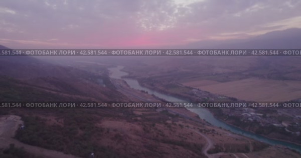 The drone flies next to the cabins of the funicular in the mountains, next to a mountain river and a small town at the foot. Стоковое видео, видеограф Aleksey Kidisyuk / Фотобанк Лори