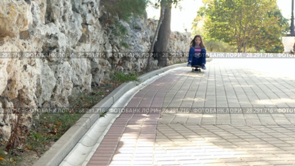 The girl is rolling down the hill on a skateboard. Стоковое видео, видеограф Tatiana Kravchenko / Фотобанк Лори