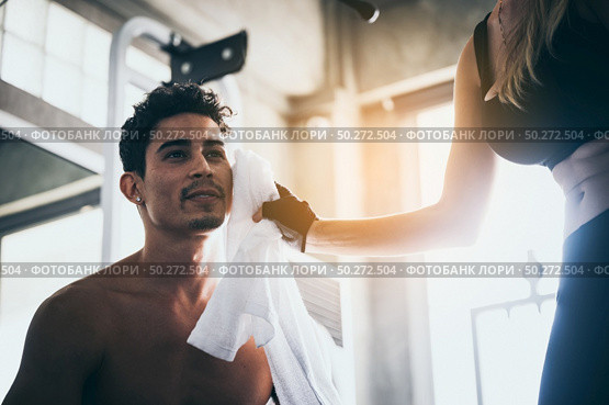 The girl uses a handkerchief to sweat the young man while exercising in the gym. Стоковое фото, агентство Ingram Publishing / Фотобанк Лори