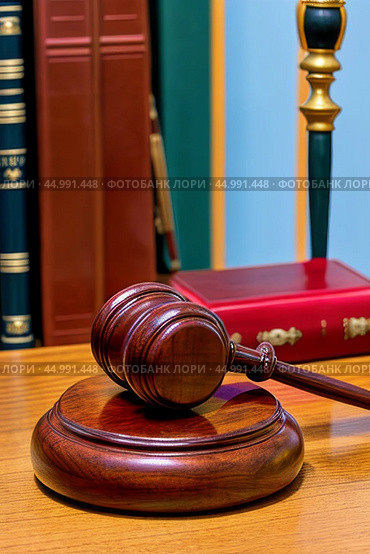 The judge's gavel lies on the table against the background of normative acts standing on the shelf. The judge's gavel is a symbol of power and the right to perform statutory actions in the position of a judge or presiding judge. Стоковое AI-изображение, AI-художник Сергей Елизарьев / Фотобанк Лори