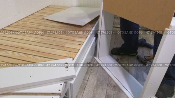 The man is assembling pull-out shelves for the sofa bed. He installs the bottom of the shelf. Стоковое видео, видеограф Vadzim Yakubovich / Фотобанк Лори