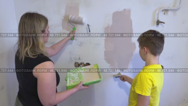 The mother and her son are busy fixing up their room, applying paint to the walls with a brush and roller. A friendly family, the new children's room in the house. Wall painting. Renovation concept. Стоковое видео, видеограф Ирина Старикова / Фотобанк Лори