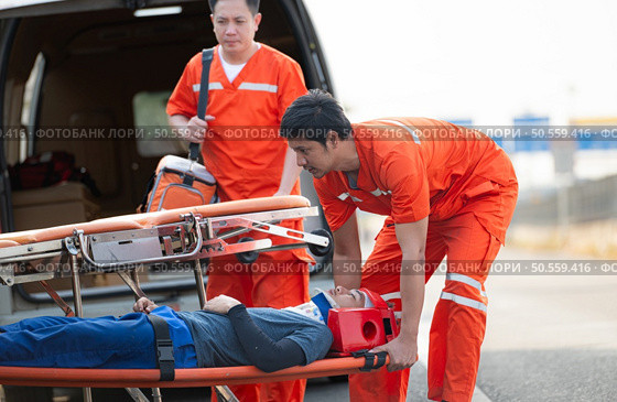 The paramedic  is assisting an injured man in an emergency situation on the road. Стоковое фото, агентство Ingram Publishing / Фотобанк Лори