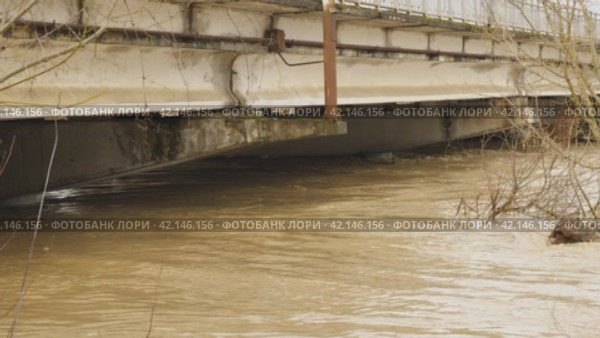 The water in river has risen to the very top of column of bridge. Flooding. Thick large concrete pillars under water. Muddy river after heavy rain. The flow of a dangerous wild river Natural disasters. Стоковое видео, видеограф Воловодов Владимир / Фотобанк Лори