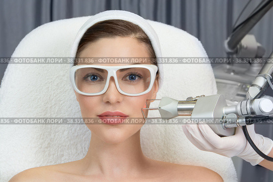 Therapist beautician makes a laser rejuvenation for the model by apparatus in a beauty salon. Стоковое фото, фотограф Юлия Тарасова / Фотобанк Лори