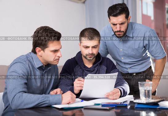 Three men worriedly discussing documents. Стоковое фото, фотограф Яков Филимонов / Фотобанк Лори