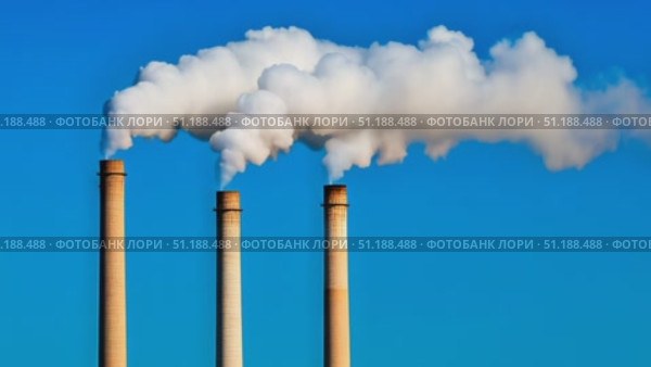 Three tall industrial chimneys release thick plumes of white smoke into the bright blue sky, symbolizing air pollution and industrial activity. The image captures the environmental impact of manufacturing and energy production. Стоковое AI-видео, аниматор Ксения Чунаева / Фотобанк Лори