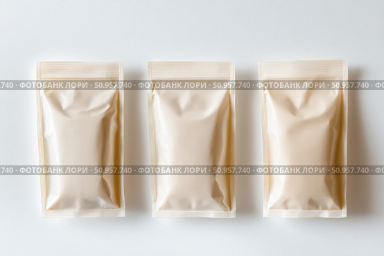 Three versatile packaging pouches varying in size are displayed on a pristine white background. Their unbranded, flexible design offers a modern touch perfect for product mockups. Стоковое AI-изображение, AI-художник Nart / Фотобанк Лори