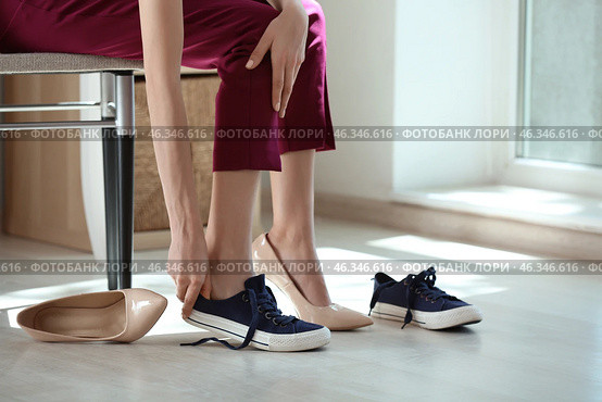Tired young woman changing shoes indoors. Стоковое фото, фотограф Pixel_shot / Фотобанк Лори
