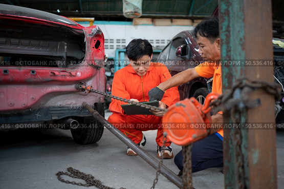 To return the automobile body to its former shape, an auto repair mechanic uses a machine to pull the car body caused by a heavy collision until it is deformed. Стоковое фото, агентство Ingram Publishing / Фотобанк Лори