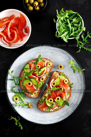 Toasts with salted salmon, arugula, green olives and cucumber, top down view. Стоковое фото, агентство Ingram Publishing / Фотобанк Лори