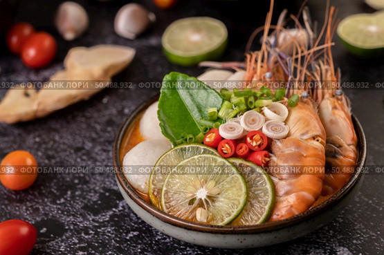 Tom Yum Kung in a bowl with tomato, chili, lemongrass, garlic, lemon, and kaffir lime leaves. Стоковое фото, агентство Ingram Publishing / Фотобанк Лори