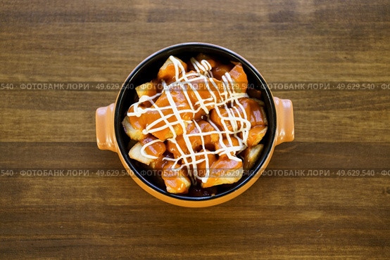 Top view of a delicious plate of patatas bravas, a typical Spanish dish, garnished with spicy sauce and served in a bowl on a wooden table in a restaurant.. Plate of patatas bravas, a typical Spanish dish, on restaurant t. Стоковое фото, агентство Ingram Publishing / Фотобанк Лори