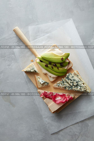 Top view of different kinds of colorful sandwiches represented on white chalkboard background. Party starter or appetizer - flat lay composition. Sandwiches with avocado, cheese, etc.. Sandwiches on white chalkboard. Стоковое фото, агентство Ingram Publishing / Фотобанк Лори