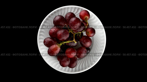 Top view of grapes with water drops in white plate rotating on black background. Стоковое фото, агентство Ingram Publishing / Фотобанк Лори
