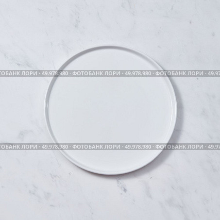 Top view of porcelain plate handmade. Ceramic glazed plate is empty on a gray background. Can be used for display or montage your products.. Decorative ceramic white plate, covered with glazed on a gray background. Traditional ceramic handcrafted. Flat lay. Стоковое фото, агентство Ingram Publishing / Фотобанк Лори