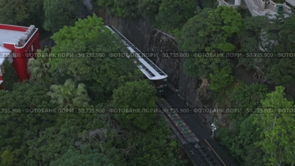 Top view of the famous green tram on the slope of Victoria Peak in Hong Kong passes, lifting visitors to the observation deck. High quality footage. Стоковое видео, видеограф Ирина Михайличенко / Фотобанк Лори