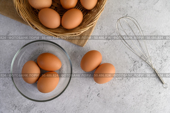 Top View three eggs in glasses bowl, blurred eggs in wicker basket and egg beater on the floor, preparing preparing for cooking food or dessert, copy space . Стоковое фото, агентство Ingram Publishing / Фотобанк Лори