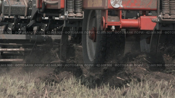 Tractor plowing a field. Close-up shot seeder planting crops in slow motion mode. Крупный план прицепного устройства для вспашки земли и посева семян. Замедленная съемка. (2017 год). Редакционное видео, видеограф EStarodubov / Фотобанк Лори