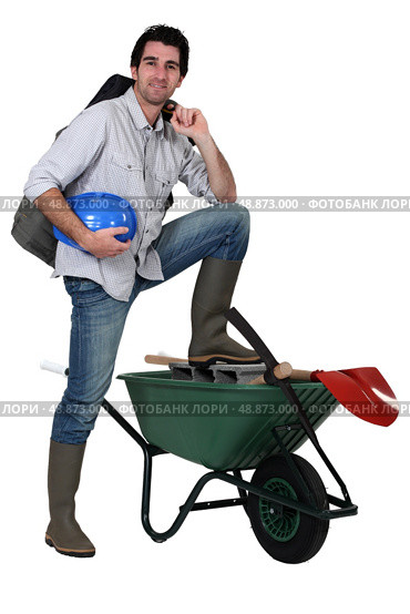 Tradesman with his foot propped up on a wheelbarrow. Стоковое фото, агентство Ingram Publishing / Фотобанк Лори