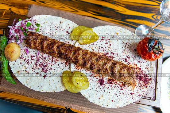 Traditional Caucasian appetizing kebab served with pickled cucumbers, stewed tomato and hot peppers on thin pita bread with fresh onion and spices. Стоковое фото, фотограф Евгений Ткачёв / Фотобанк Лори