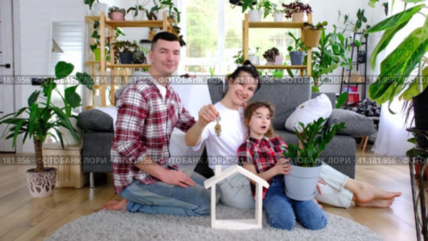 Traditional family with child are enjoying new home, sitting on the sofa and holding the roof. Mortgage, insurance and protection, buying and moving into your own home, green house with potted plant. Стоковое видео, видеограф Ольга Симонова / Фотобанк Лори