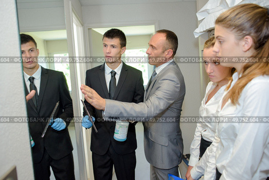 Trainee cleaning a mirror under supervision. Стоковое фото, агентство Ingram Publishing / Фотобанк Лори