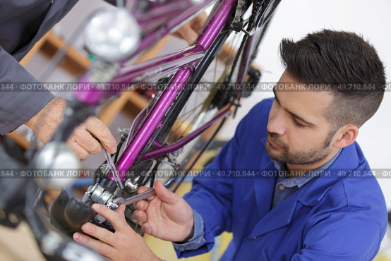Trainee mechanic working on bicycle. Стоковое фото, агентство Ingram Publishing / Фотобанк Лори