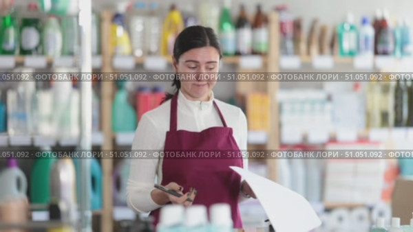 Trainee saleswoman reacts emotionally to the paperwork, she is irritated and dissatisfied. Woman experiences burnout at work. Salesperson works with papers in the warehouse of a household compartment of a supermarket. Стоковое видео, видеограф Яков Филимонов / Фотобанк Лори