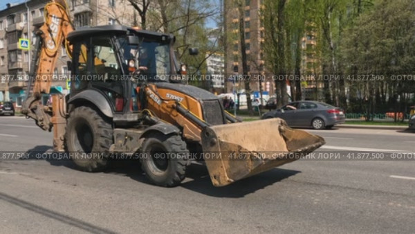 Трактор с большим ковшом быстро едет по улице Москвы (2023 год). Редакционное видео, видеограф Галина / Фотобанк Лори