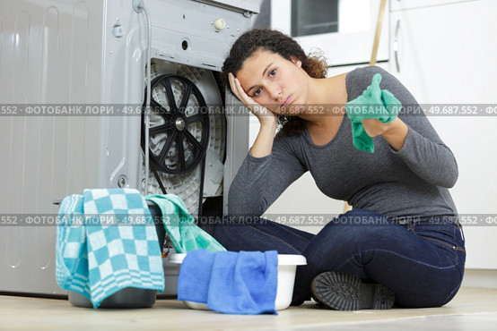 troubled woman looking at leaking at machine in kitchen. Стоковое фото, агентство Ingram Publishing / Фотобанк Лори