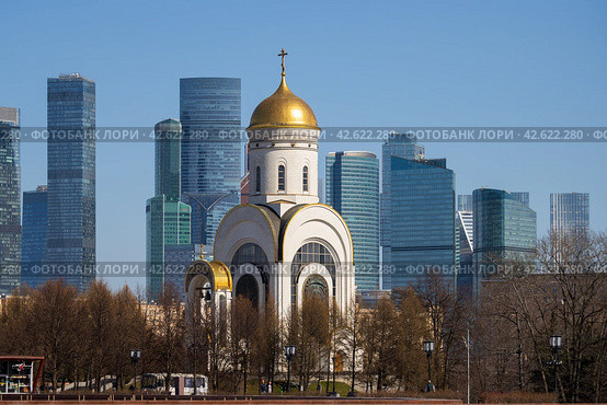 Церковь Георгия Победоносца, Поклонная гора, Москва, Россия. Вид на церковь и небоскрёбы московского международного делового центра «Москва-Сити». Современный городской пейзаж. Красивая церковь на фоне высотных зданий. (2023 год). Редакционное фото, фотограф Андрей Степанов / Фотобанк Лори