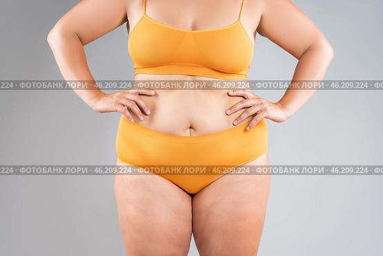 Tummy tuck, flabby skin on a fat belly, abdomen with obesity and cellulite, saggy stomach, plastic surgery concept on gray background. Стоковое фото, фотограф Станислав Тарко / Фотобанк Лори