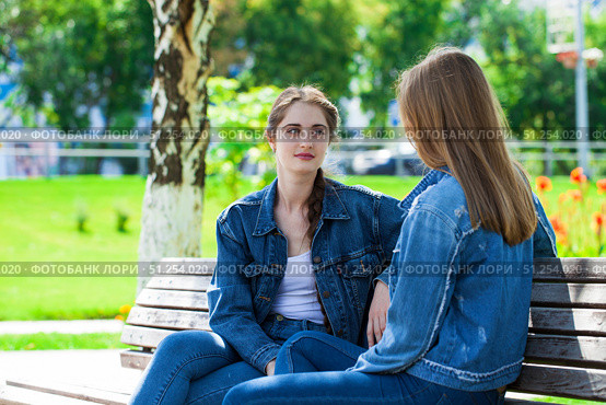 Two beautiful girlfriends are talking in a park sitting on a bench. Стоковое фото, фотограф Андрей Аркуша / Фотобанк Лори