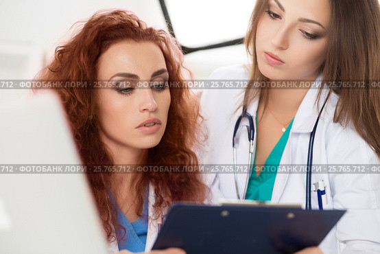Two female doctors looking at patient information form. Стоковое фото, фотограф Людмила Дутко / Фотобанк Лори