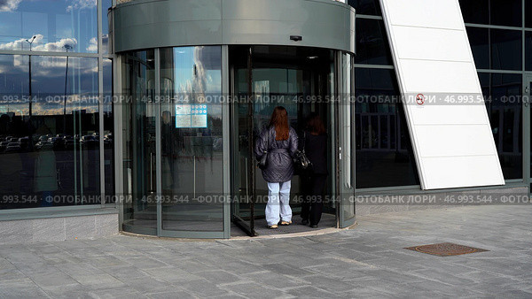 Two female friends entering modern shopping center or office building. Стоковое фото, фотограф David Kashakhi / Фотобанк Лори