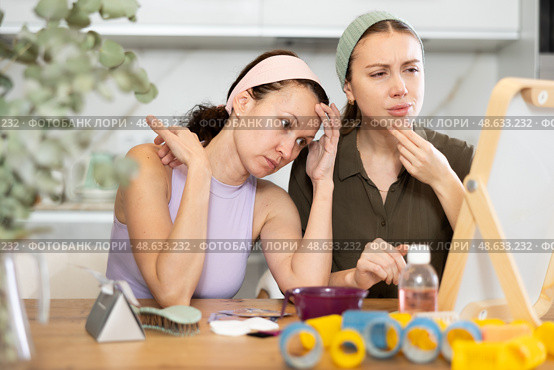 Two female friends examining faces in vanity mirror at home. Стоковое фото, фотограф Яков Филимонов / Фотобанк Лори